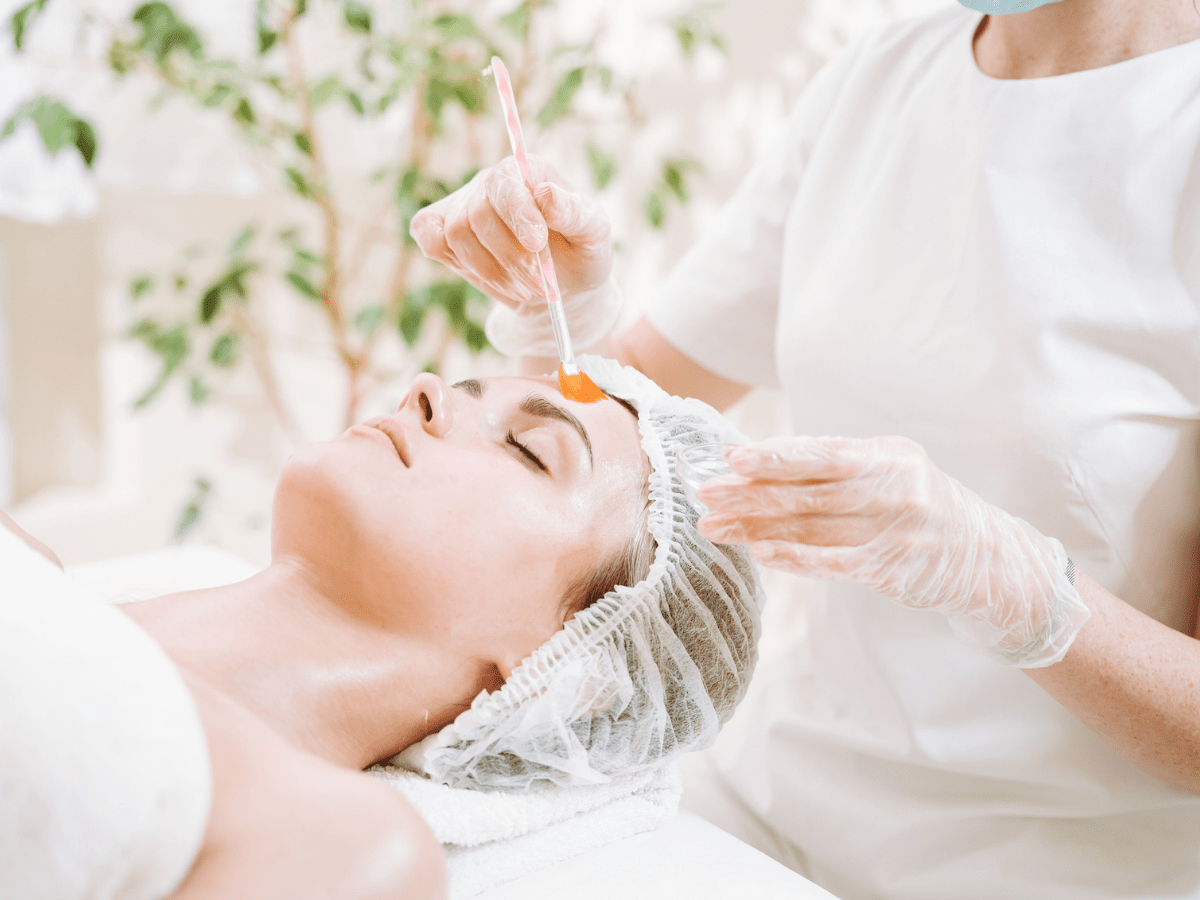 A woman receiving a chemical peel treatment at a dermatologist office to reverse sun damage.