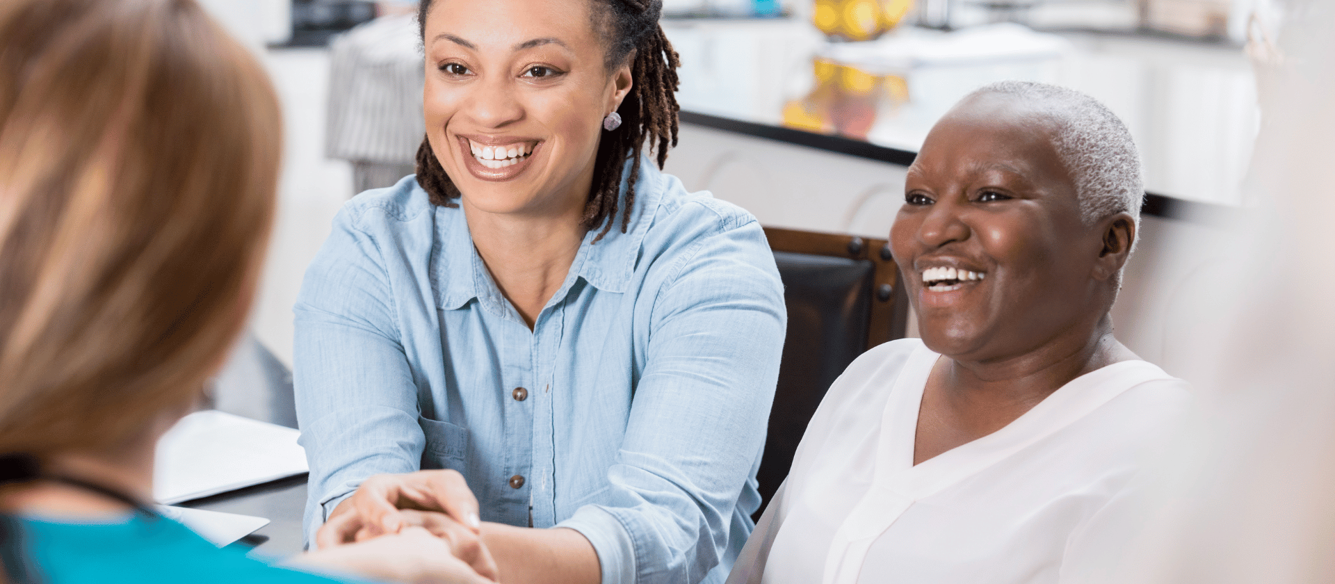 A woman and her mother at a dermatology consultation shaking the hand of a dermatologist.